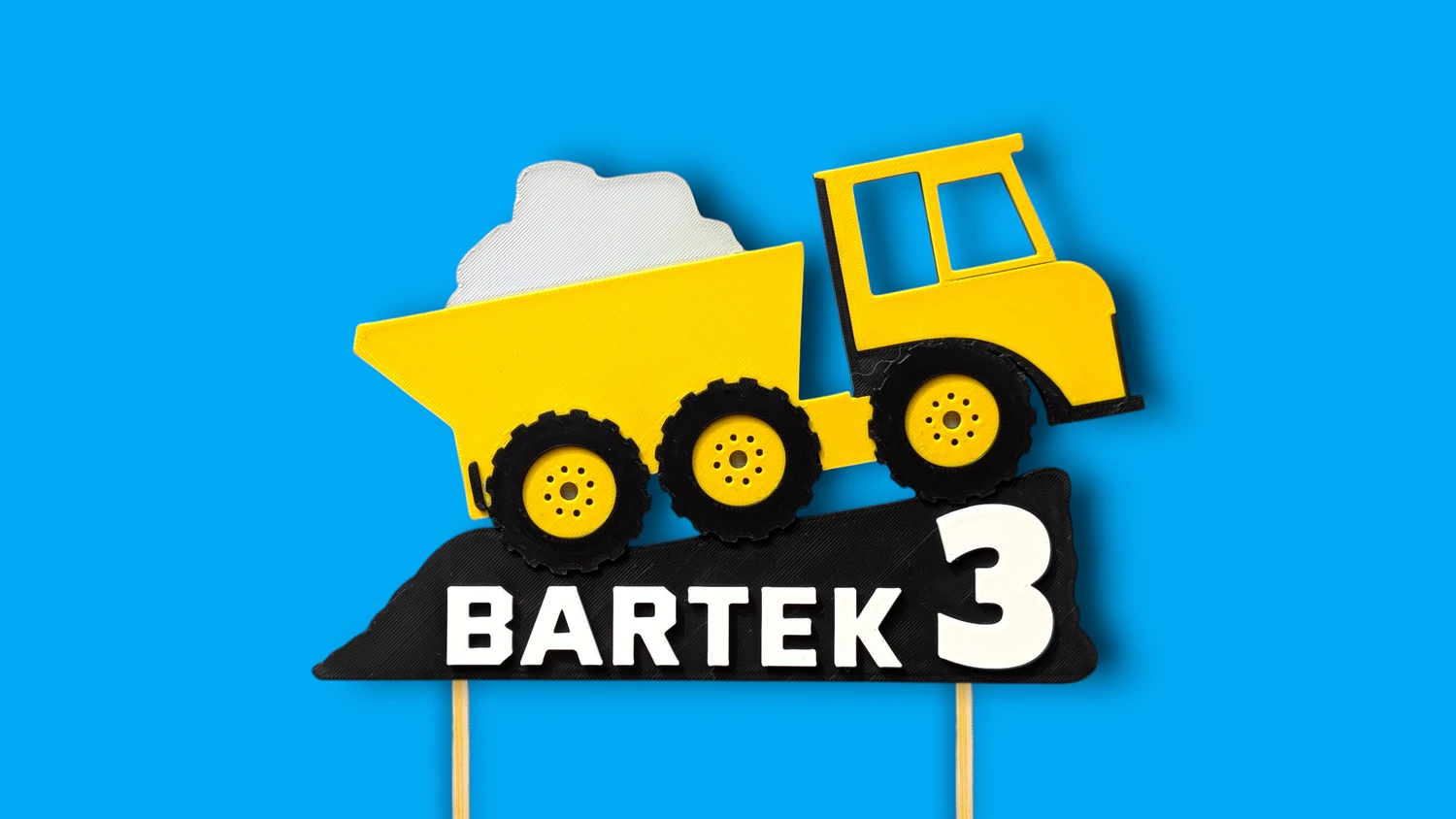 Personalizowany topper wywrotka na niebieskim tle – zbliżenie pod kątem na efekt 3D, grubość kół i detale imienia